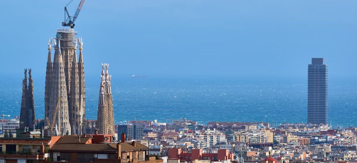 A vibrant view of Barcelona's skyline with La Sagrada Familia and the Mediterranean Sea in the background.