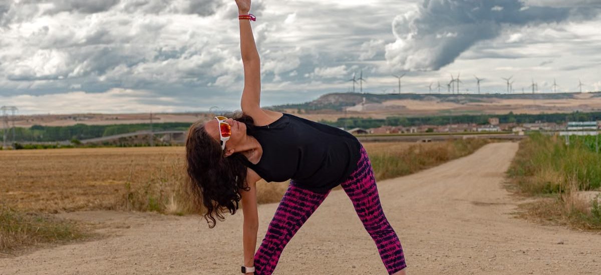 Outdoor fitness scene of a woman stretching on a dirt path in Soto de Cerrato amidst scenic landscapes.